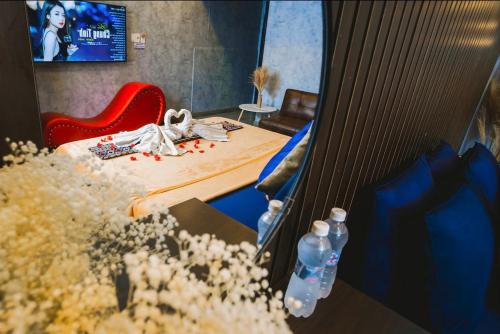 a room with a bed and a red chair and water bottles at MIS HOSTEL Cần Thơ in Can Tho