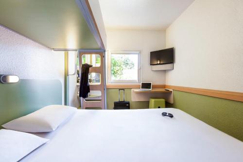 a bedroom with a large white bed and a window at ibis budget Poitiers Nord Futuroscope in Chasseneuil-du-Poitou