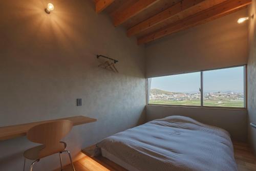 Schlafzimmer mit einem Bett, einem Schreibtisch und einem Fenster in der Unterkunft YHouse in Kumamoto