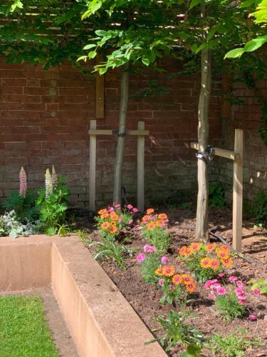 a garden with flowers and crosses on a brick wall at Townhouse - free parking, garden & games room in Exeter
