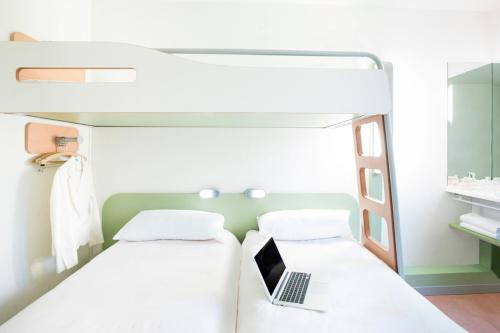 a bedroom with a bunk bed with a laptop on it at ibis budget Poitiers Nord Futuroscope in Chasseneuil-du-Poitou