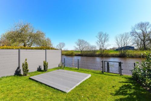 un muelle en la hierba junto a un cuerpo de agua en Ferienhaus HarleSand, en Carolinensiel