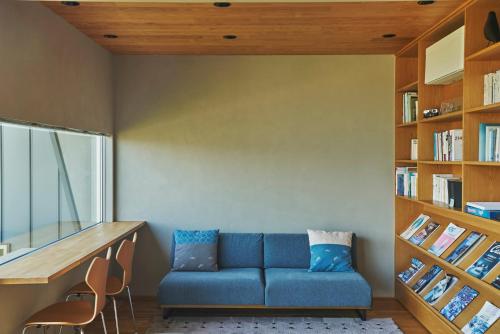 a living room with a blue couch and bookshelves at YHouse in Kumamoto