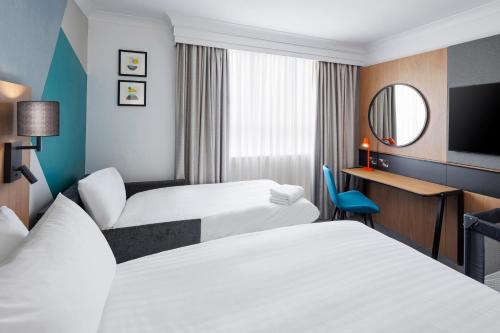 a hotel room with two beds and a mirror at Holiday Inn London-Bexley by IHG in Bexley