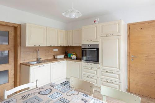 a kitchen with white cabinets and a table and chairs at Počitniška Hiša Pr Martinovih in Postojna