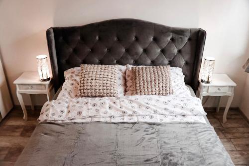 a bed with a black headboard and two night stands at Lavender Hill Apartment in Gdańsk