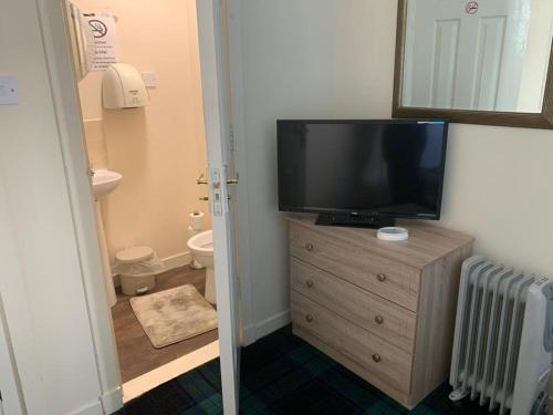 a bathroom with a television on top of a dresser at Budget Rooms in Inverness