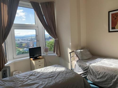 a bedroom with two beds and a television and a window at Budget Rooms in Inverness