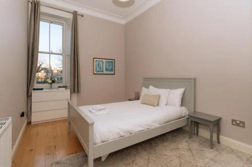 um quarto com uma cama com lençóis brancos e uma janela em Beautiful Home In Stockbridge Edinburgh em Edimburgo