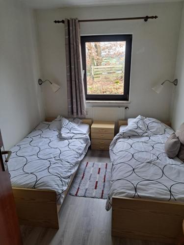 two beds in a room with a window at Haus Eifelblick in Gönnersdorf