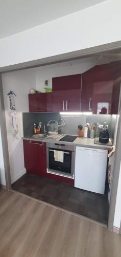 a small kitchen with red cabinets and a stove at Grand studio lumineux à côté des plages in Dinard