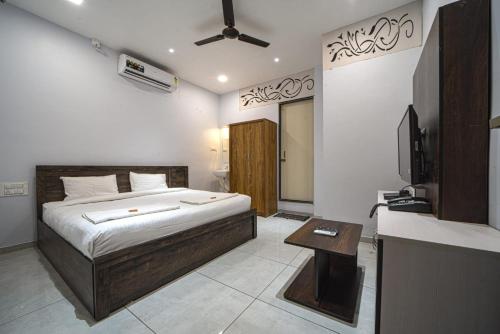 a bedroom with a bed and a bathroom with a television at Hotel Saheb in Kolhapur