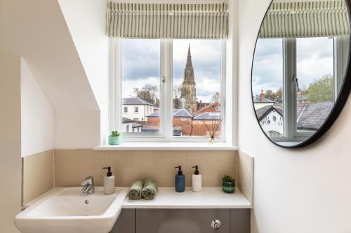 a bathroom with a sink and two windows with a mirror at 4 Bed City House with Private Garden and Parking in Winchester