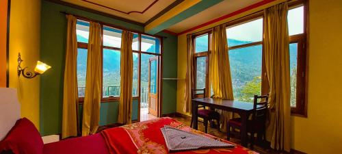 una camera da letto con scrivania, tavolo e finestre di La Vaca India Manali a Manāli