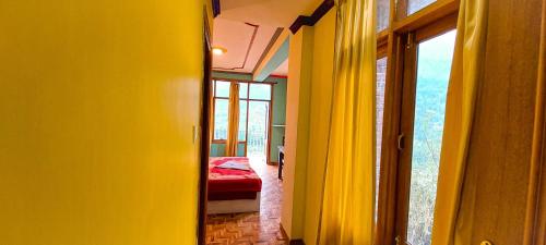 a yellow hallway with a room with a bed and windows at La Vaca India Manali in Manāli