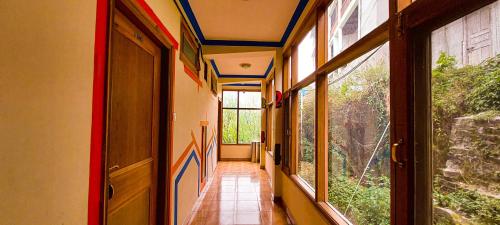 an empty hallway with blue ceilings and windows at La Vaca India Manali in Manāli