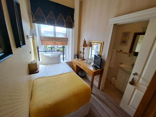 a bedroom with a bed and a desk and a television at The Ambassador Townhouse in Southport