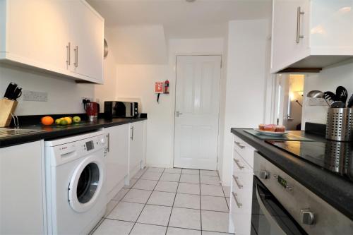 a kitchen with white cabinets and a washer and dryer at Signature - Atholl House Glasgow Airport in Paisley