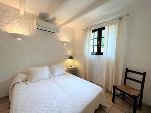 - une chambre avec un lit blanc, une chaise et une fenêtre dans l'établissement Résidence Marie Diane - Appart vue mer et piscine G, à Propriano