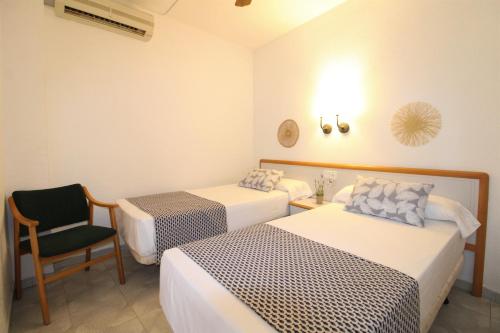 a hotel room with two beds and a chair at Hotel Canada in Benicàssim