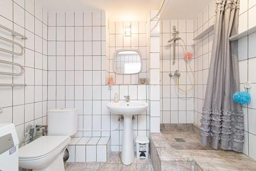 Baño de azulejos blancos con aseo y lavamanos en Vilnius view apartments (95 sqm) en Vilna