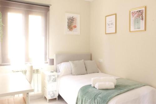 a white bedroom with a bed and a window at Habitación centro Oviedo cerca de estación de buses y trenes in Oviedo