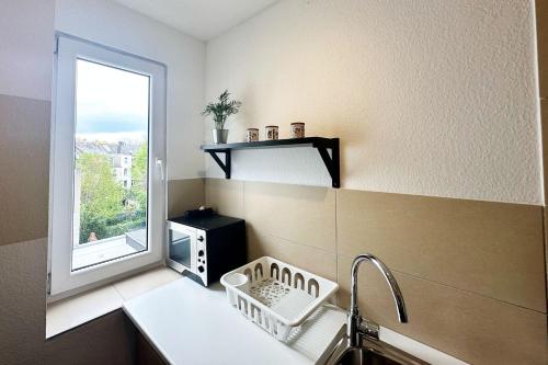 een kleine keuken met een wastafel en een raam bij Spacious & Cozy Apartments in Krefeld