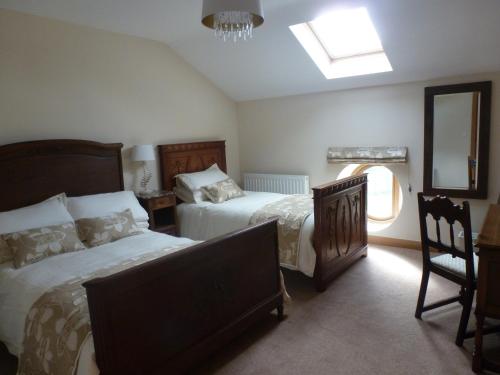 a bedroom with two beds and a mirror and a window at Mile House Barn Bed & Breakfast in Nantwich