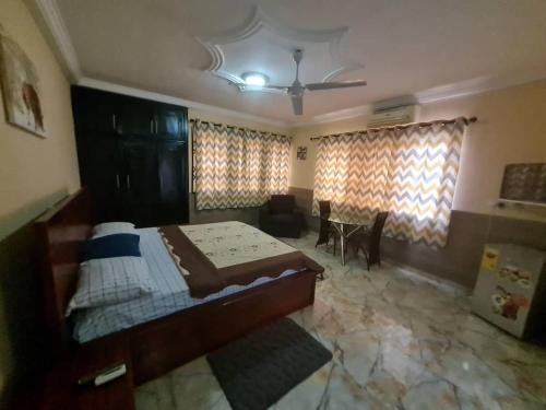 um quarto com uma cama, uma mesa e cortinas em NESTA BARRON -Home Away from Home em North Legon