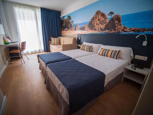 a bedroom with a large bed with a painting on the wall at Hotel Don Juan Tossa in Tossa de Mar