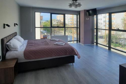 a bedroom with a large bed and large windows at Zora in Blagoevgrad