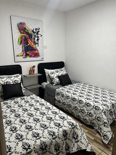 Zimmer mit 2 Betten, einem Sofa und einem Gemälde in der Unterkunft Apartamento central en Itagui in Itagüí
