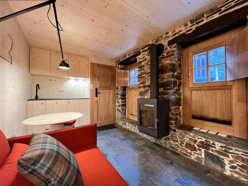 a living room with a red couch and a stone wall at Casas do Talasnal in Lousã