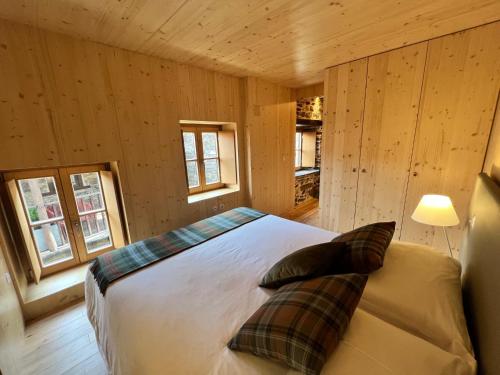 1 dormitorio con 1 cama en una habitación con paredes de madera en Casas do Talasnal en Lousã