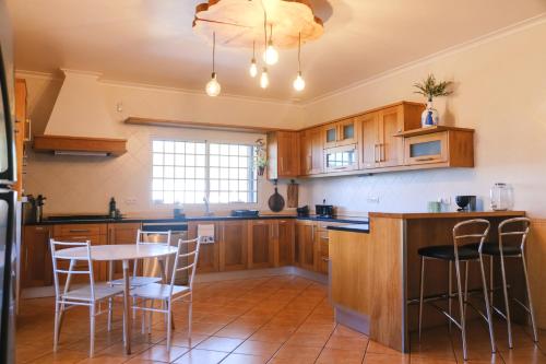 een keuken met houten kasten en een tafel en stoelen bij LAVA Açores Coliving & Coworking in Ribeira Grande