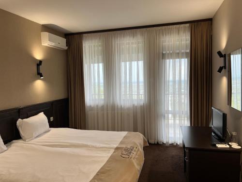 a hotel room with a bed and a desk with a television at Chiflika Family Hotel in Asenovgrad