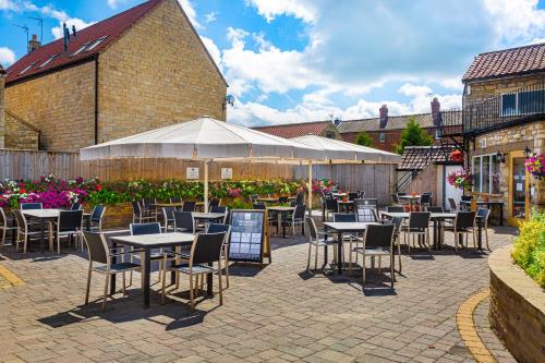 a patio with tables and chairs in a courtyard at The Feathers Hotel, Helmsley, North Yorkshire - The Coaching Inn Group in Helmsley