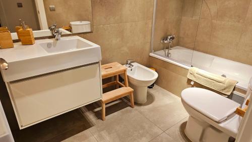 ein Badezimmer mit einem Waschbecken, einem WC und einer Badewanne in der Unterkunft Apartamento diseño con jardín privado a 100 metros del mar in Torredembarra