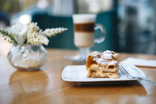 a piece of cake on a plate on a table with a cup of coffee at So Stay Hotel in Gdańsk