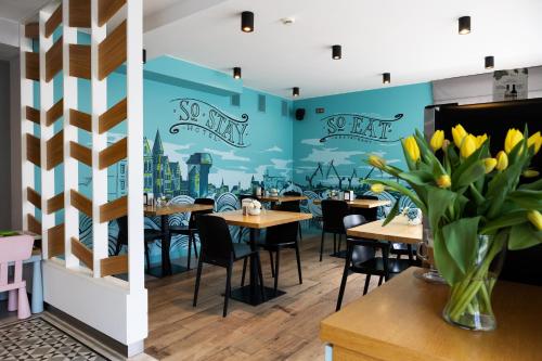 a restaurant with tables and chairs and a mural of a city at So Stay Hotel in Gdańsk