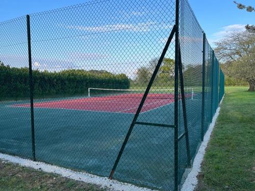 a fence on a tennis court with a net at Maison Terracotta, le calme aux portes de Poitiers in Saint-Julien-lʼArs