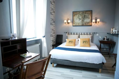 1 dormitorio con cama con almohadas amarillas y escritorio en Logis Auberge De L'ombrée, en Combrée