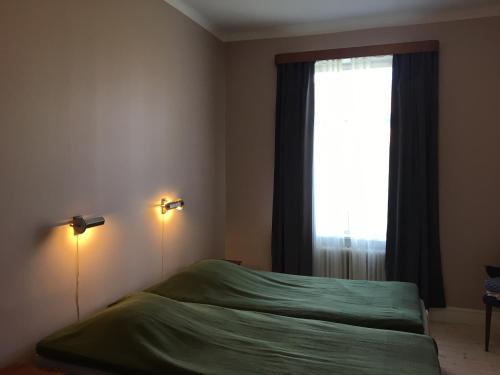 a bedroom with a green bed and a window at Vitaby Järnvägshotell in Vitaby