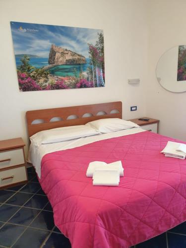 a bedroom with a pink bed with towels on it at Hotel Mareluna Ischia in Ischia