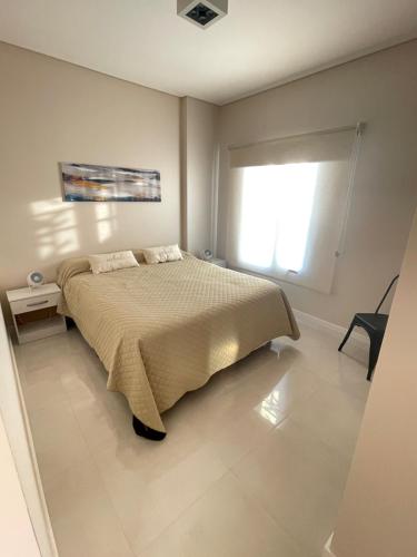 Un dormitorio con una cama grande y una ventana en Depto. a Estrenar, Terraza Vista al Mar en Puerto Madryn
