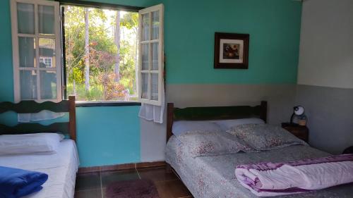 a bedroom with two beds and a window at Pousada do Tie - Rio Preto MG in São José do Rio Preto