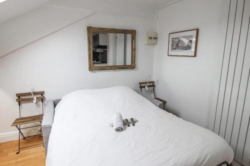 a bedroom with a white bed with a mirror on the wall at Charming studio 3 min away from Château de Versailles - Welkeys in Versailles