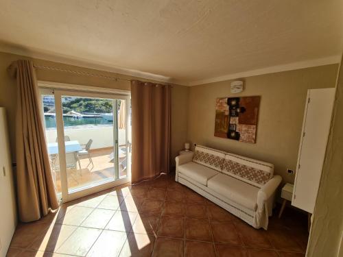 uma sala de estar com um sofá e uma porta de vidro deslizante em La chicca del porto em Santa Teresa Gallura