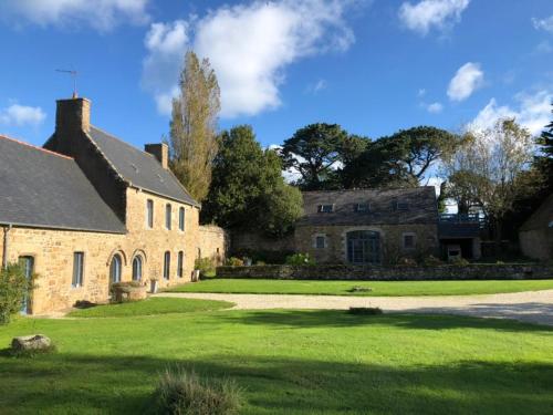 an old stone house with a green lawn at Les écolodges Sous Le Phare in Louannec