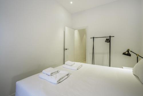 a white bed with two folded towels on it at The White Flats Sant Antoni in Barcelona